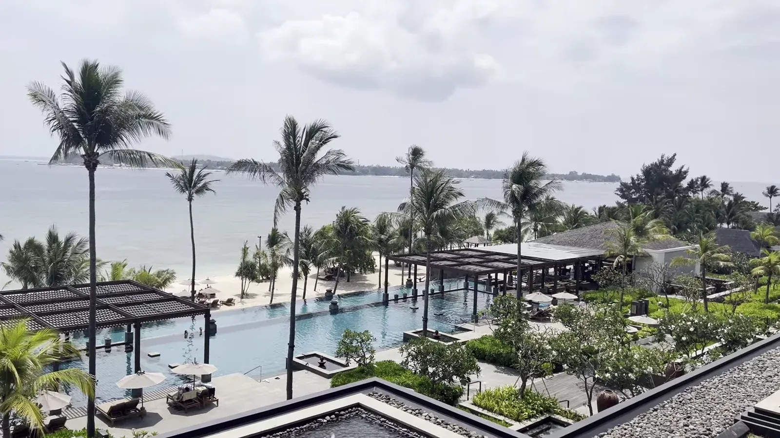 View from the suite balcony at The Sira Lombok: the pool, palms and the calm north-coast sea