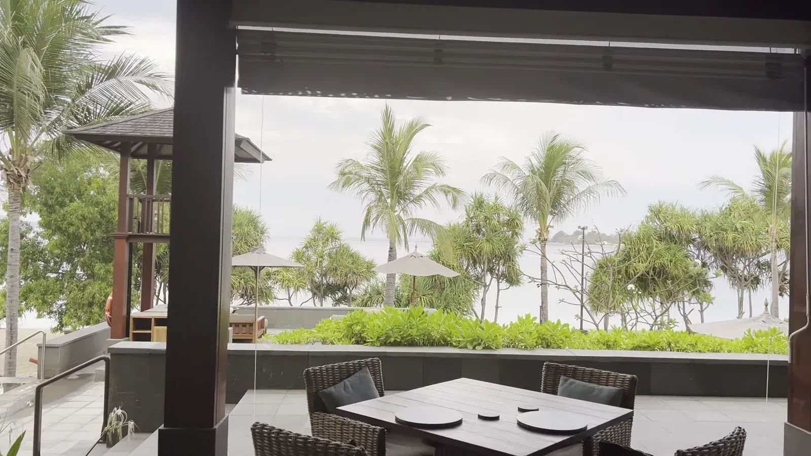 Tables at Medsa, The Sira Lombok, set under the open pavilion with the beach and sea beyond